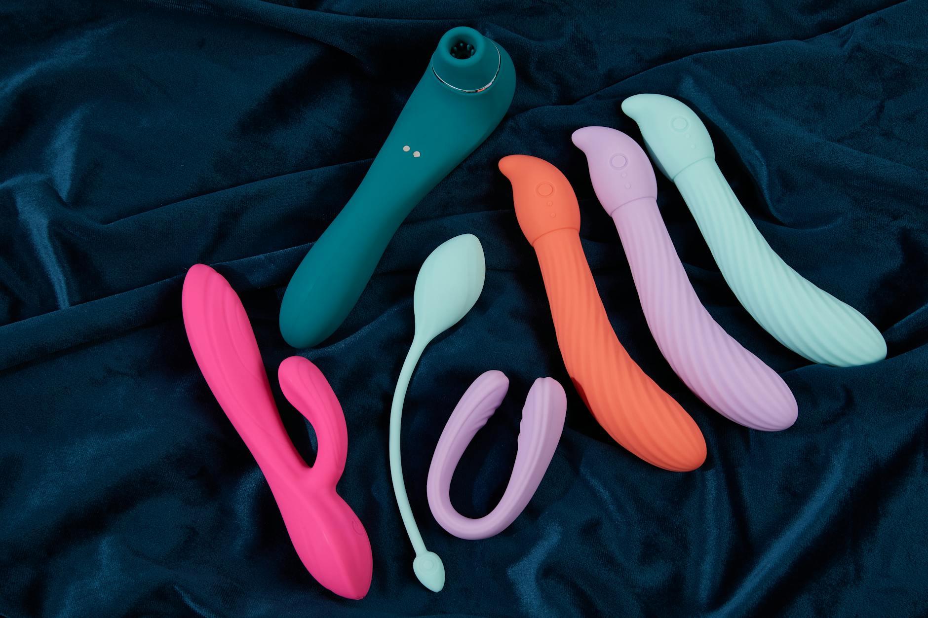 Mão segurando vibrador azul e rosa em posição contemplativa