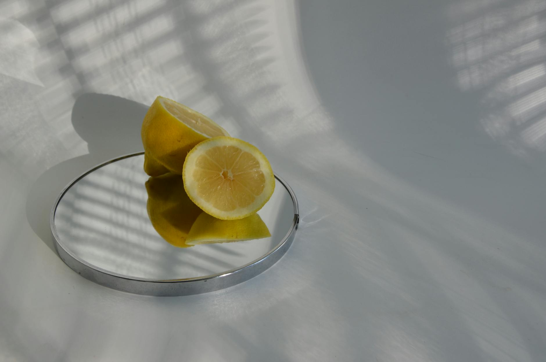 Limões fatiados em espelho com sombras suaves, destacando o design minimalista da fotografia