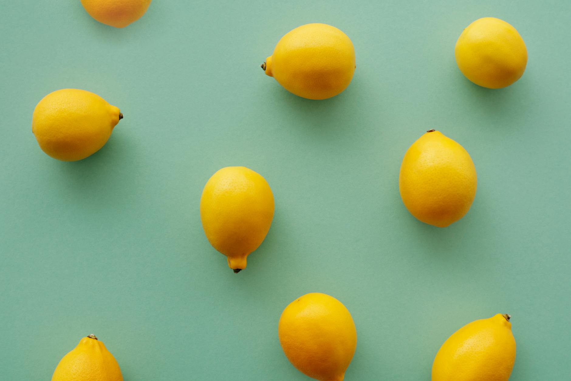Limões amarelo-brilhantes dispostos em composição flat lay em fundo pastel, simbolizando frescor e sensualidade