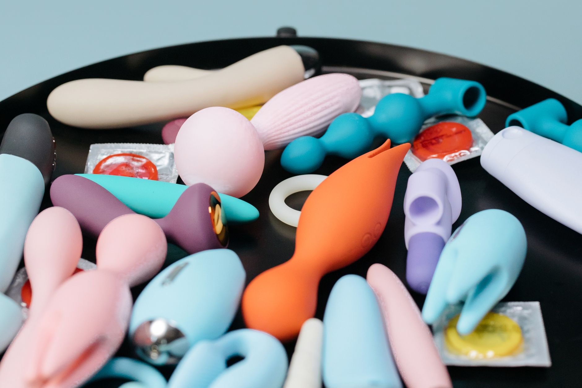 Mão de mulher segurando um vibrador pessoal azul contra um suéter de tricô