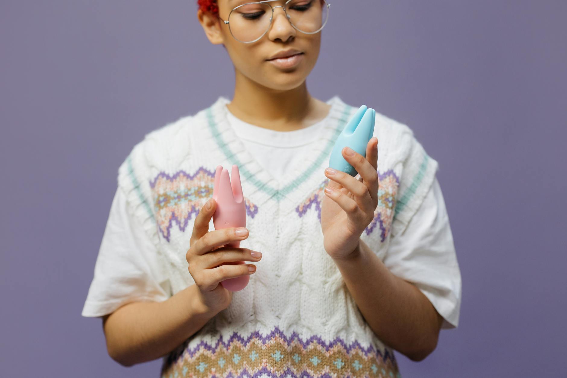 Mulher segurando vibradores coloridos em pose contemplativa, representando exploração do prazer e bem-estar.
