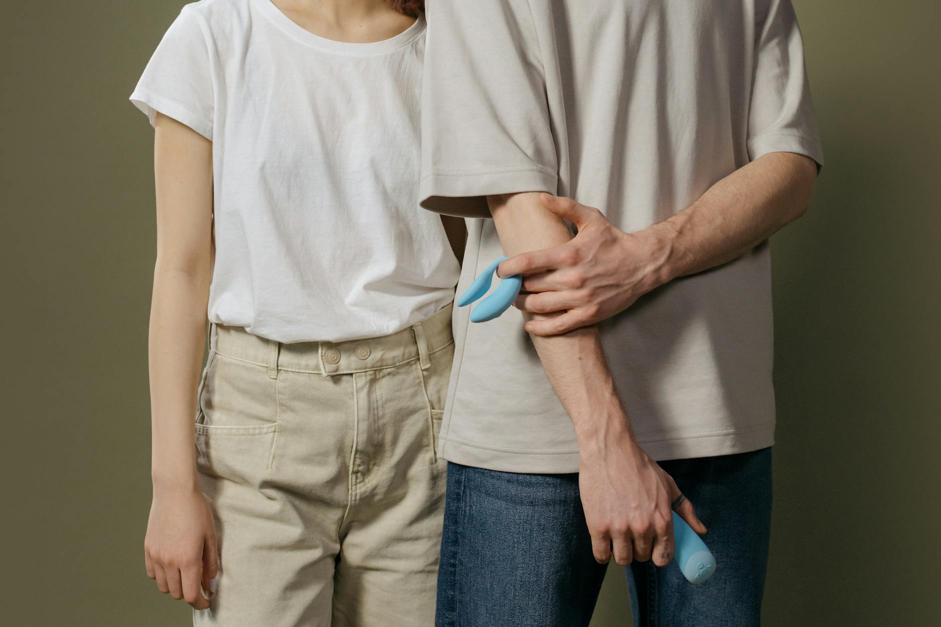 Mão segurando um vibrador azul sobre uma tigela decorativa de vidro
