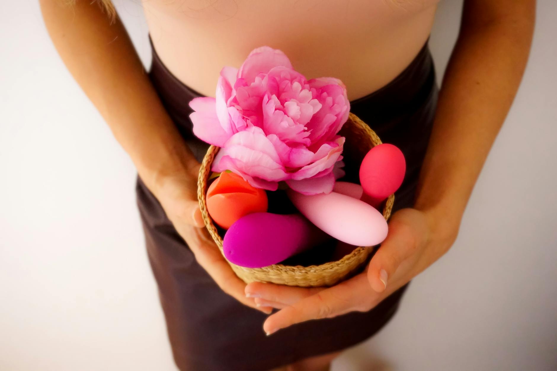 Mão segurando vibrador laranja contra fundo roxo minimalista, mostrando sensualidade moderna
